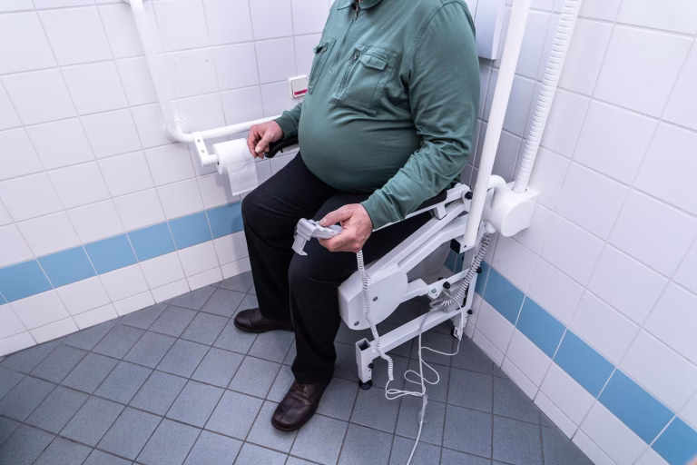 Herr nutzt die Aufstehhilfe R2Dfx zum sicheren und einfachen Aufstehen von der Toilette